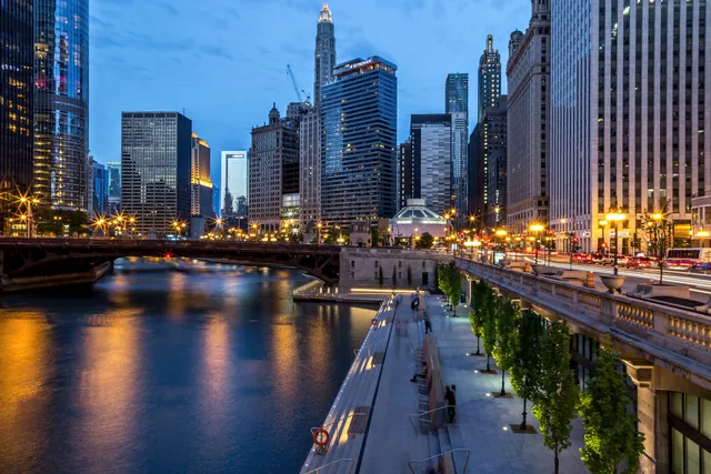 The Chicago Riverwalk at dusk, lit bridges and towers