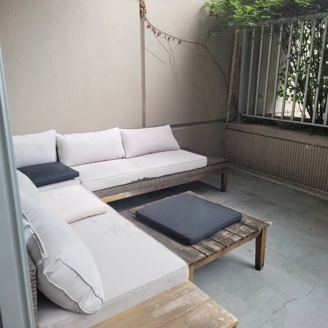 Unit W907 — the furnished corner of the private terrace: outdoor sectional and coffee table against the building wall
